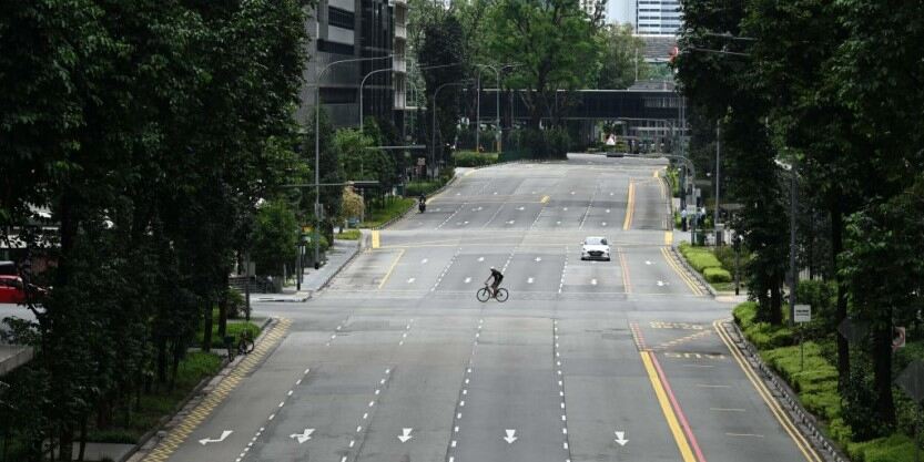 cyclist crossing the road with trees on both side