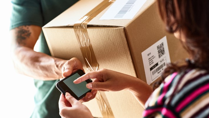 Woman signing digitally after receiving the parcel from the delivery partner