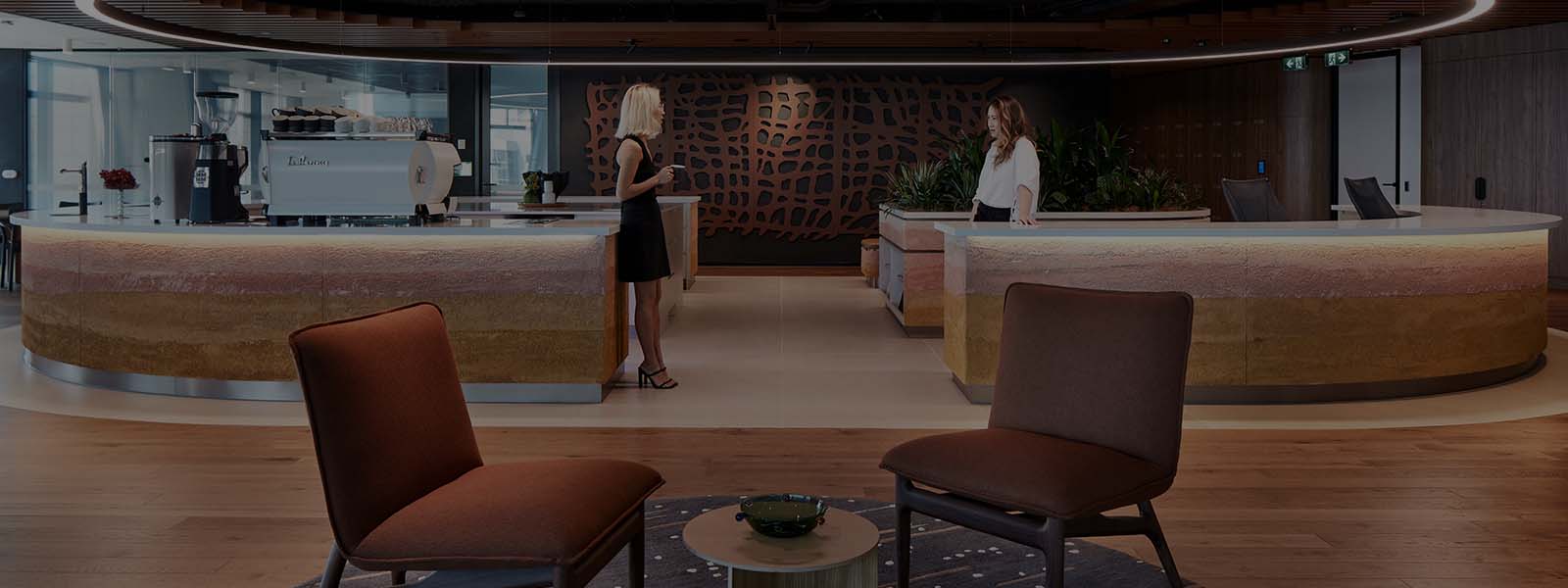 Two female employees talking while having coffee in the breakout area inside JLL office building