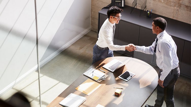 Two people shake hands in an office