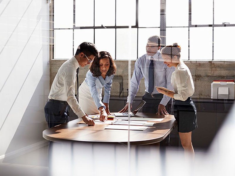 A group of men and women collaborate together in a meeting room.