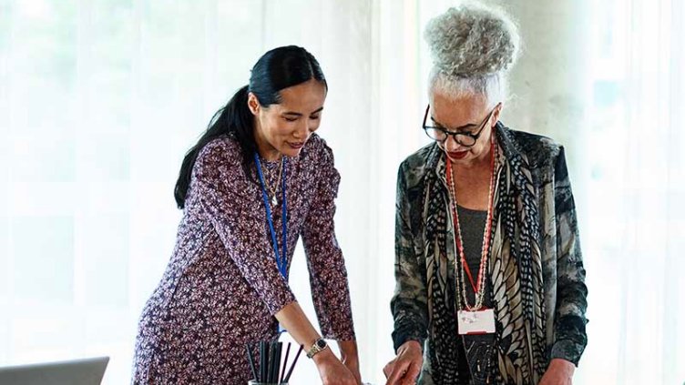 Two Businesswomen brainstorming in an office using adhesive notes before the meeting