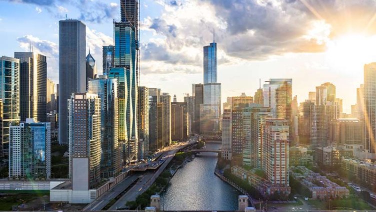 Sunset casts a warm glow over the Chicago skyline, highlighting the city's iconic buildings in the distance.
