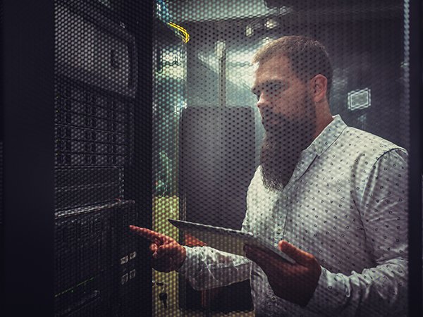 Young IT engineer inspecting data center servers