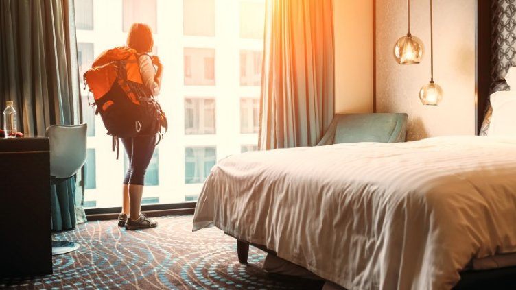 Girl Carring Bag and looking outside the hotel window